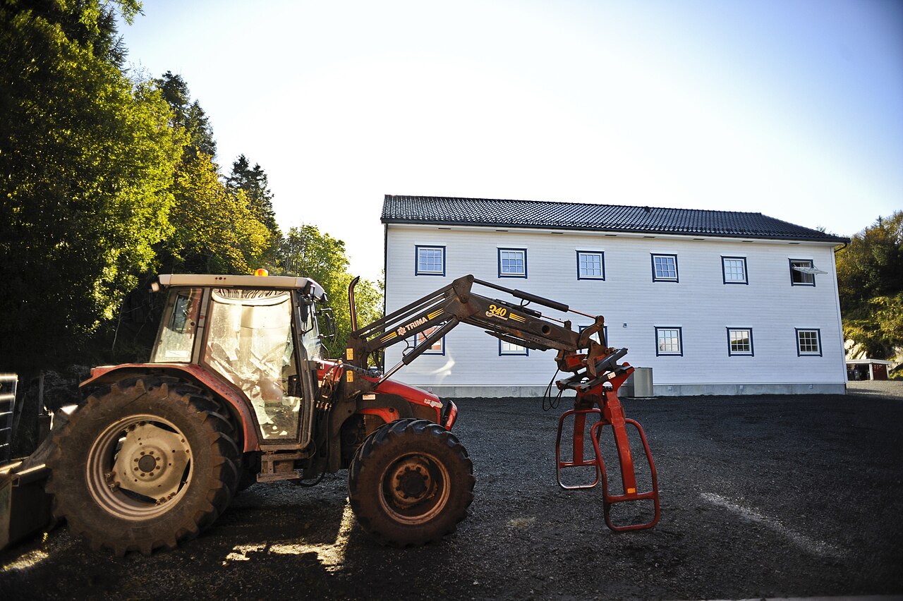 Rød Massey Ferguson med Trima-frontlaster og balleklype i Bergen