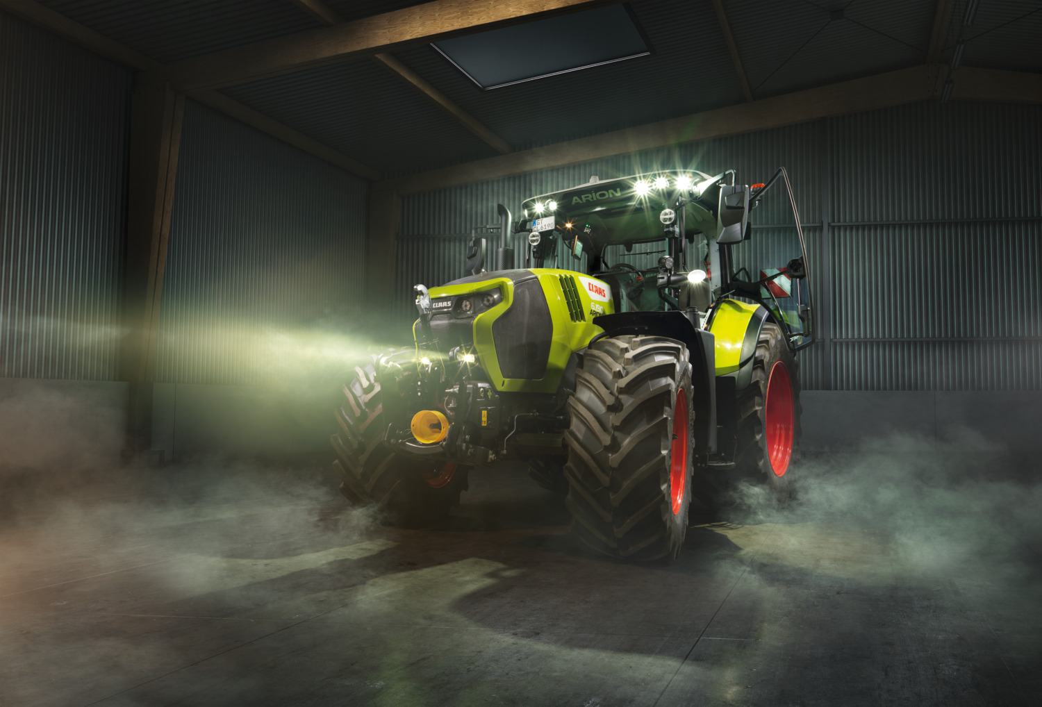 CLAAS-traktor med tente arbeidslys i en maskinhall