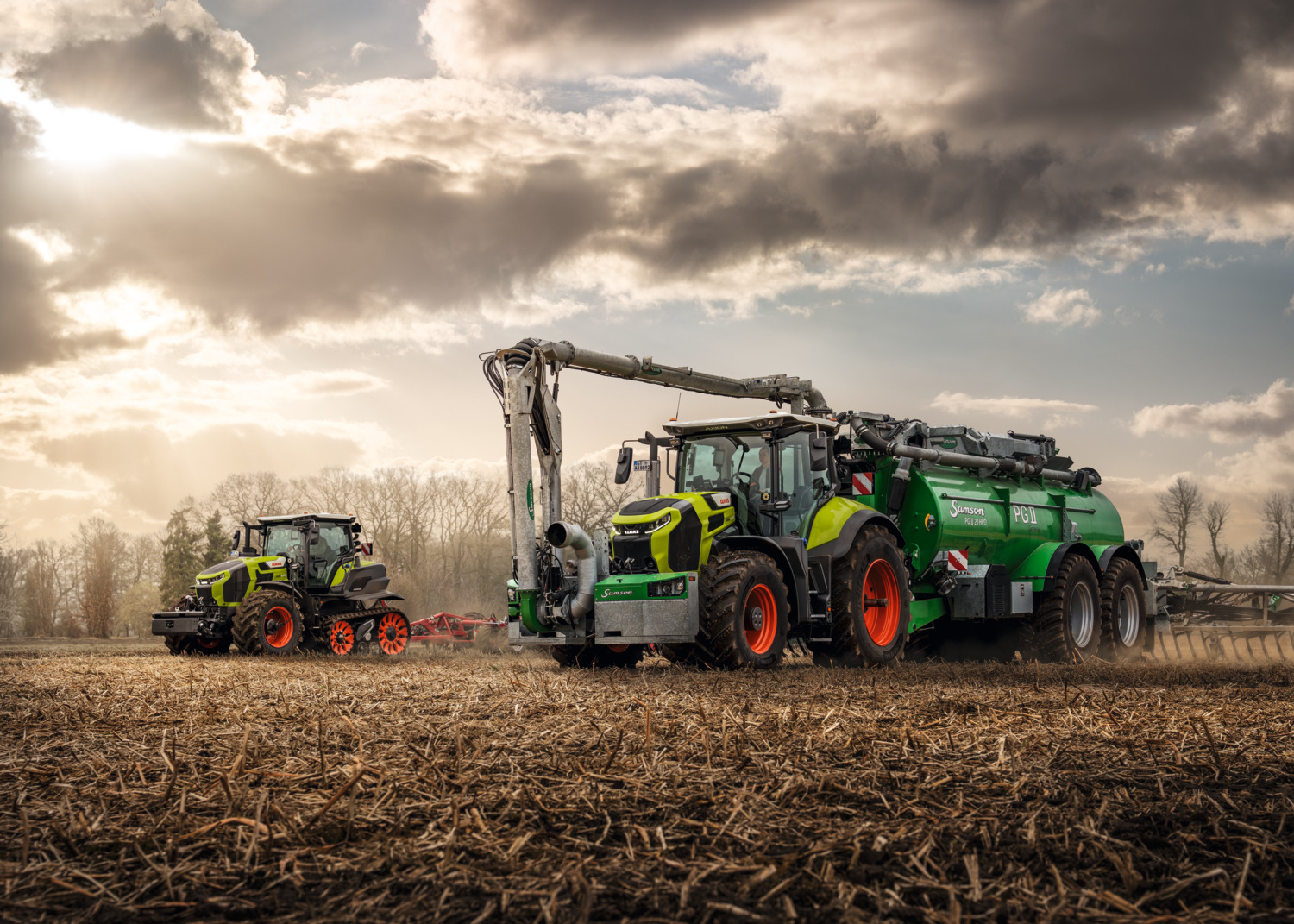 CLAAS-traktor med stor SAMSON-gjødselvogn og fyllearm på et jorde