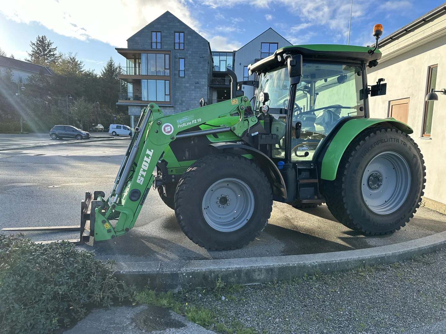 Deutz-Fahr og STOLL-laster sett fra siden, med løftearmer, sylindre og pallegaffel synlig