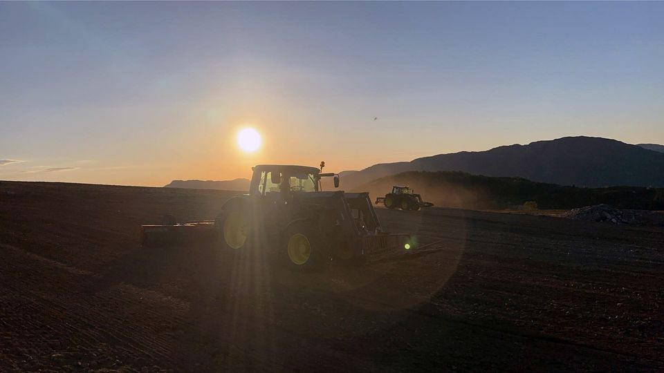 John Deere i jordarbeid på Vestlandet ved solnedgang