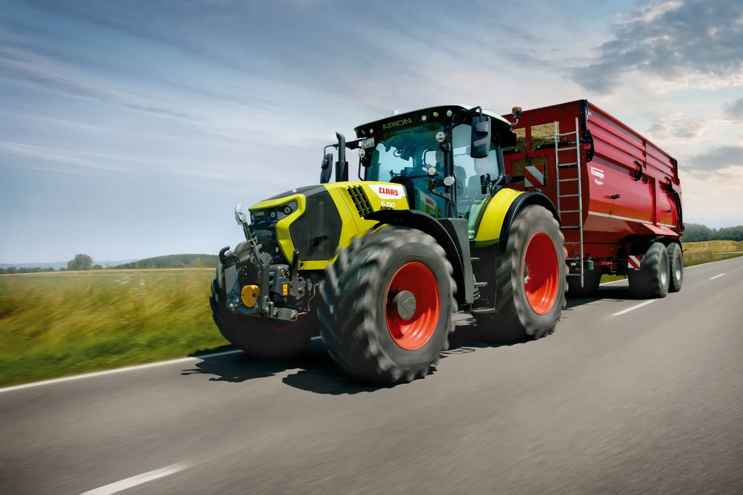 CLAAS ARION 6 med rød tilhenger under transport på vei