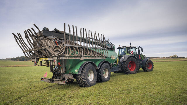 Traktor med gjødselvogn og brede hjul i en eng