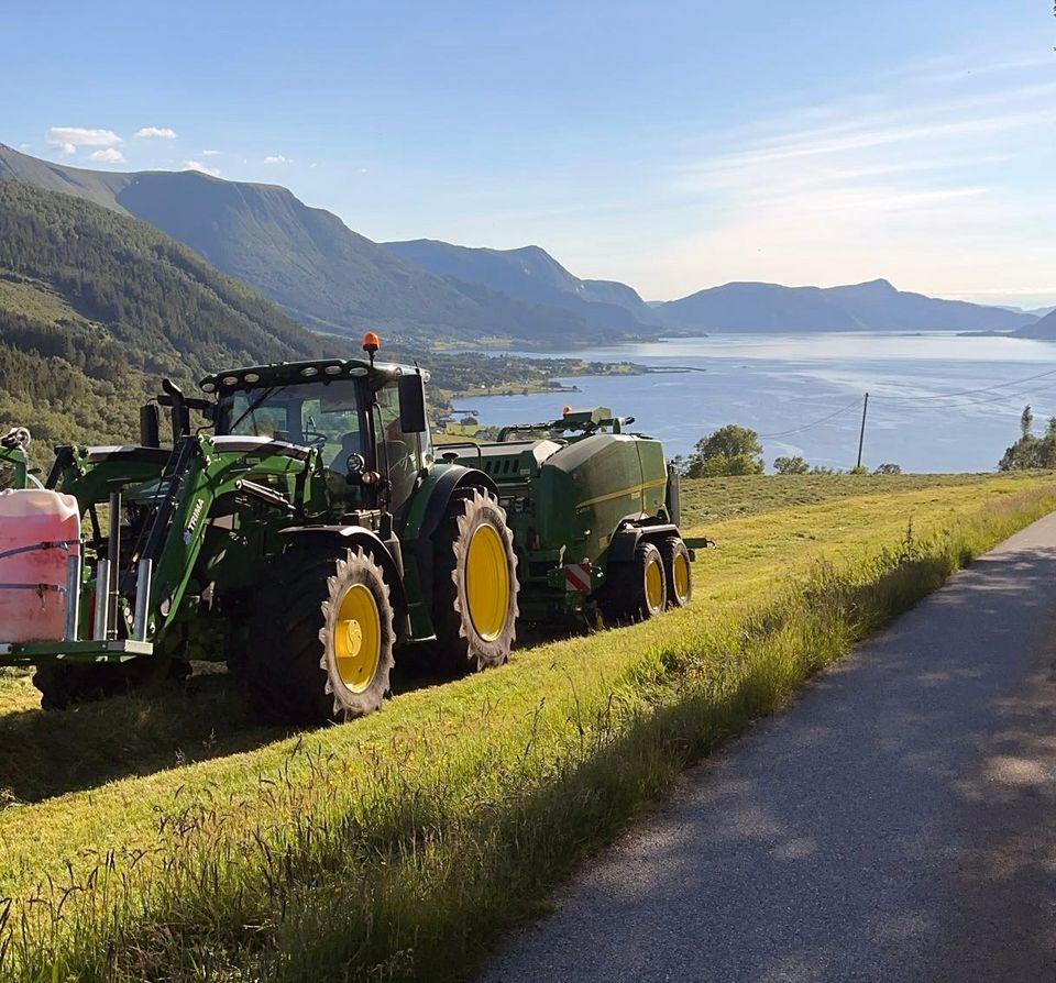 John Deere med rundballepresse på et jorde ved fjorden på Rovde