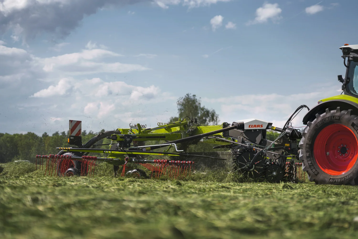 CLAAS LINER-samlerive bak en traktor i grasarbeid