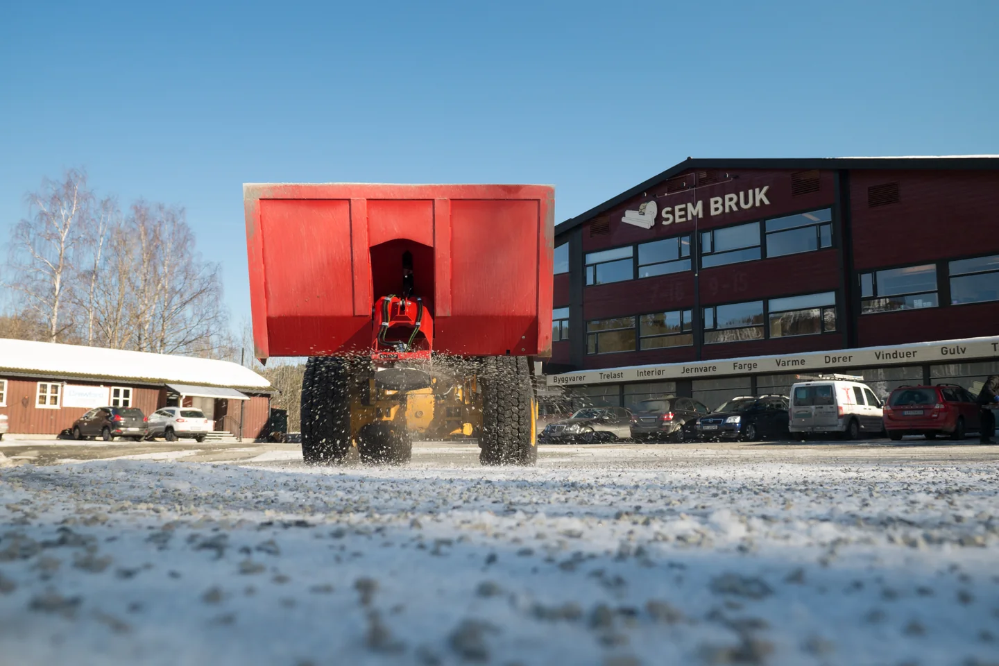 Tokvam TSA 2100 på hjullaster sprer grus fra tallerkenen under beholderen
