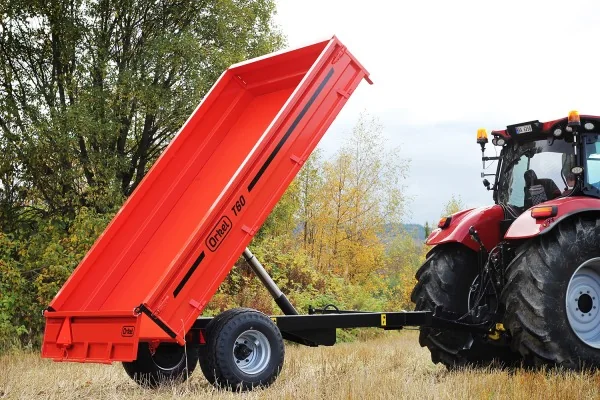 Orkel T60 tilhenger bak en rød traktor, med planet løftet og tippsylinderen synlig