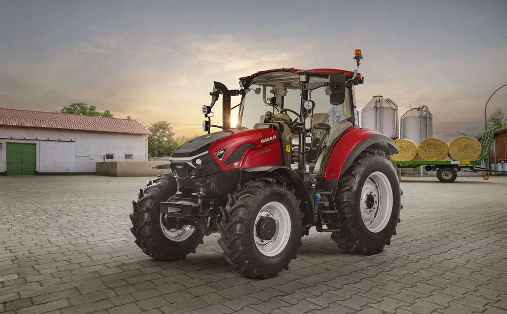 Case IH Farmall 120M på en gårdsplass med rundballer i bakgrunnen