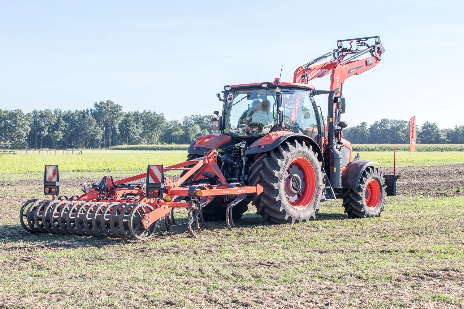 Kubota M6-132 med frontlaster og samlerive under grasarbeid