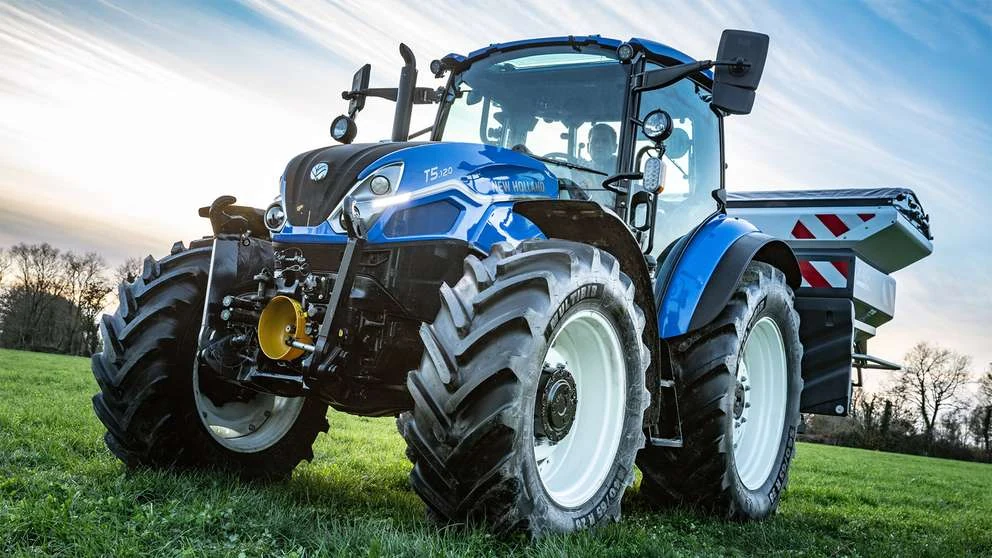 New Holland T5 Dual Command med frontløft og bakmontert redskap på et jorde